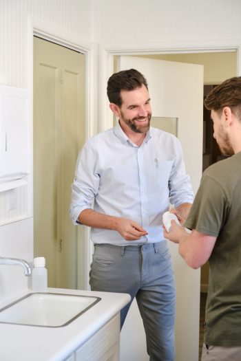 A man giving a bottle of medicine to another man.